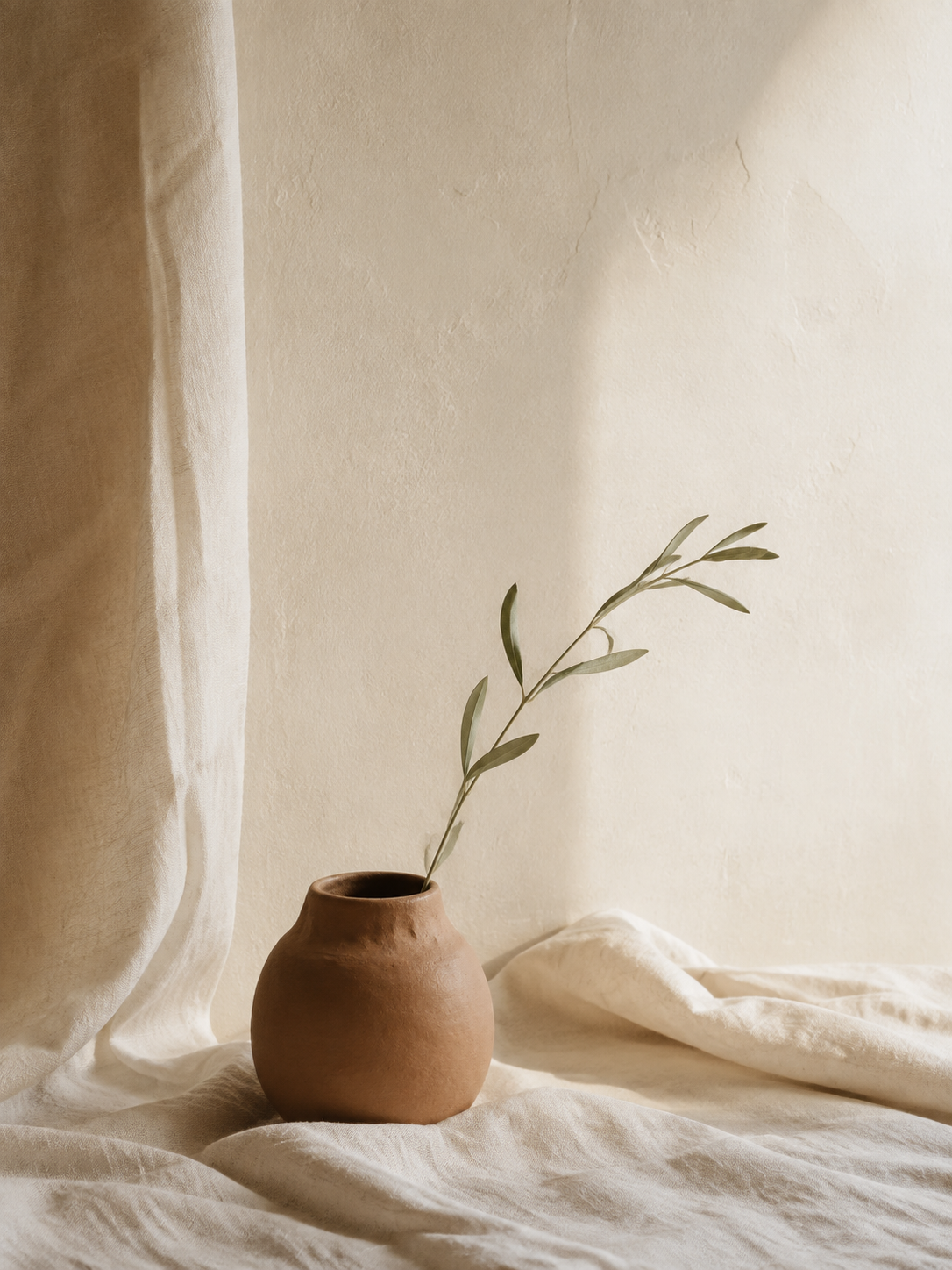 A warm, quiet still life with linen, clay and botanicals